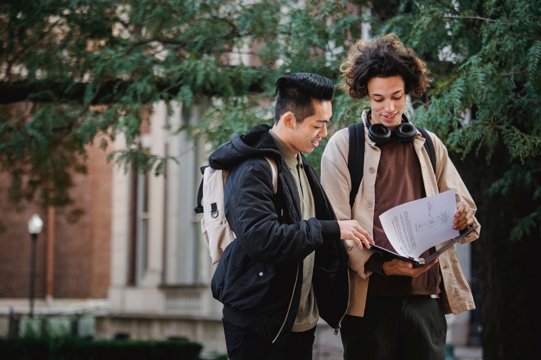 Two international students comparing university documents on campus