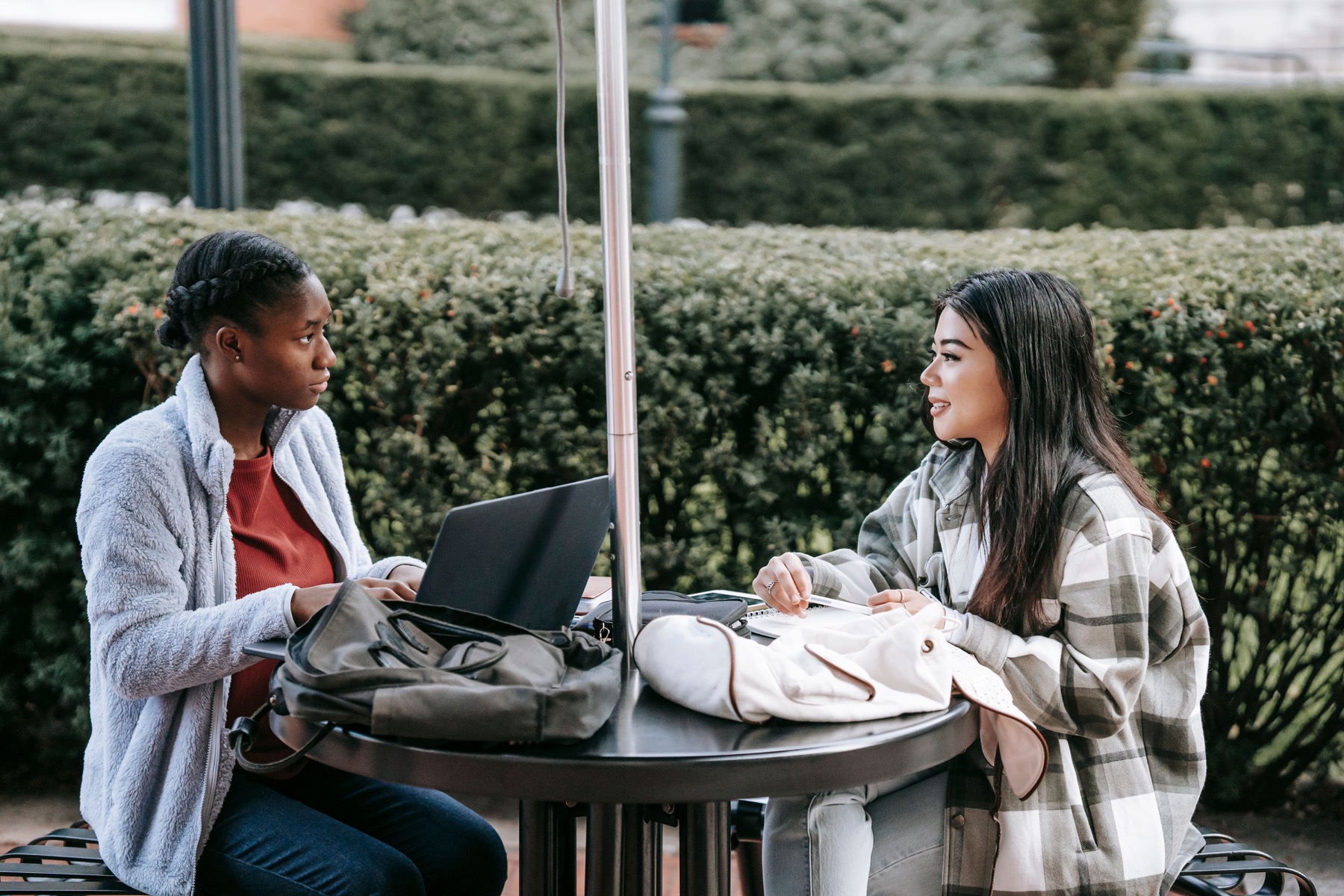 Two university students discuss a technology project on a laptop outdoors on campus
