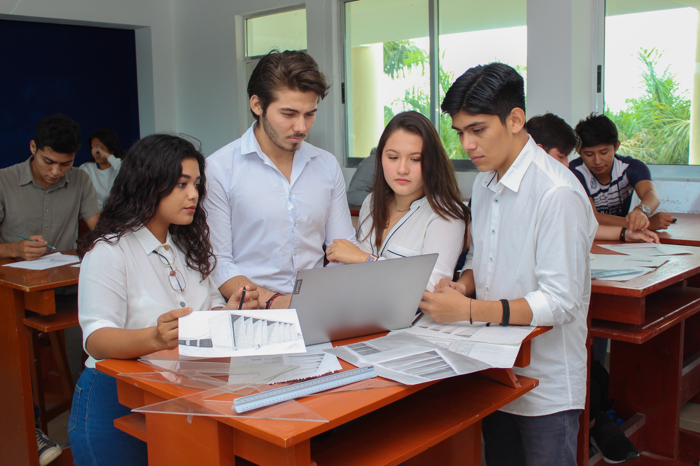 Architecture students discuss drawings and a design project together in a university studio