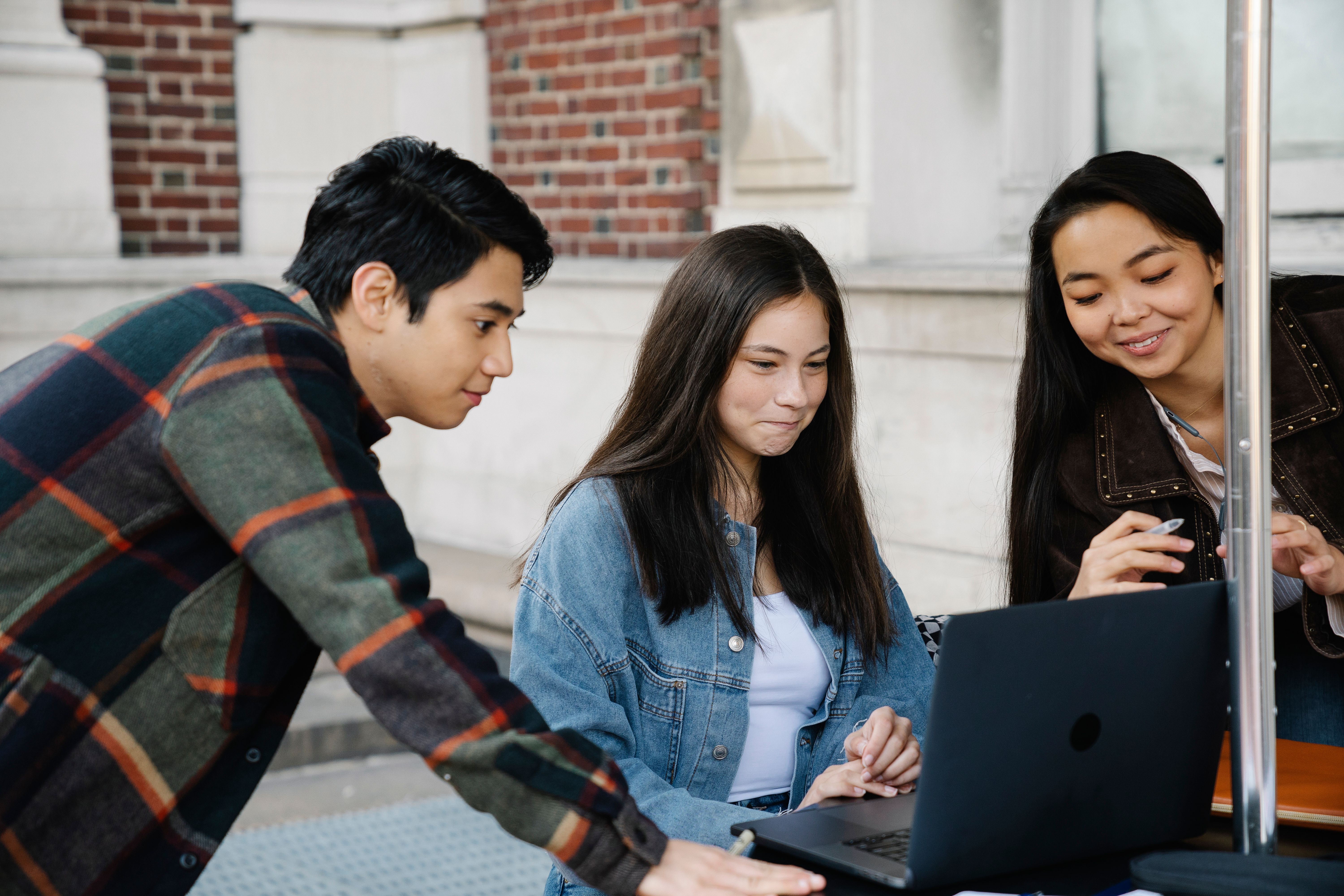 Three students completing a university application together on a laptop