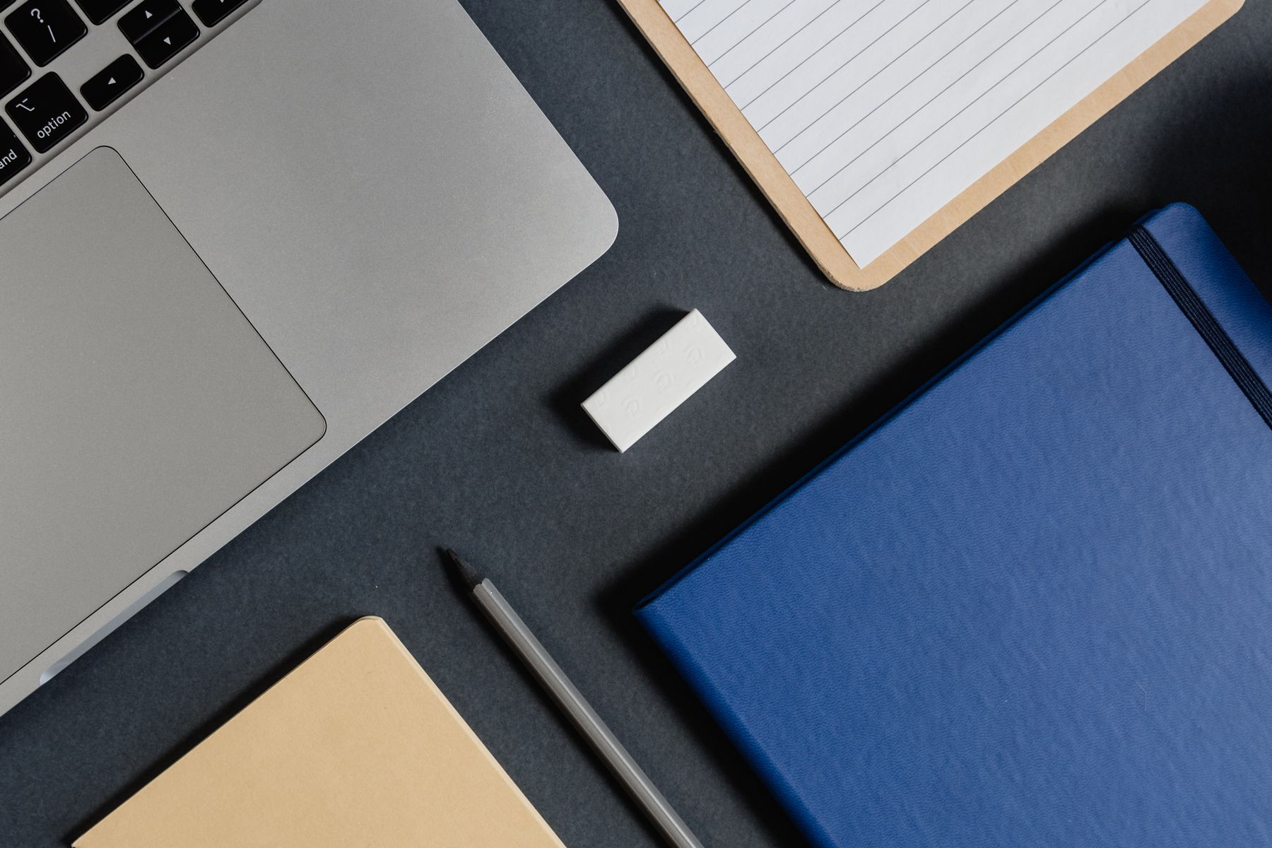 Laptop, notebooks and a pen arranged on a desk for planning an overseas university application