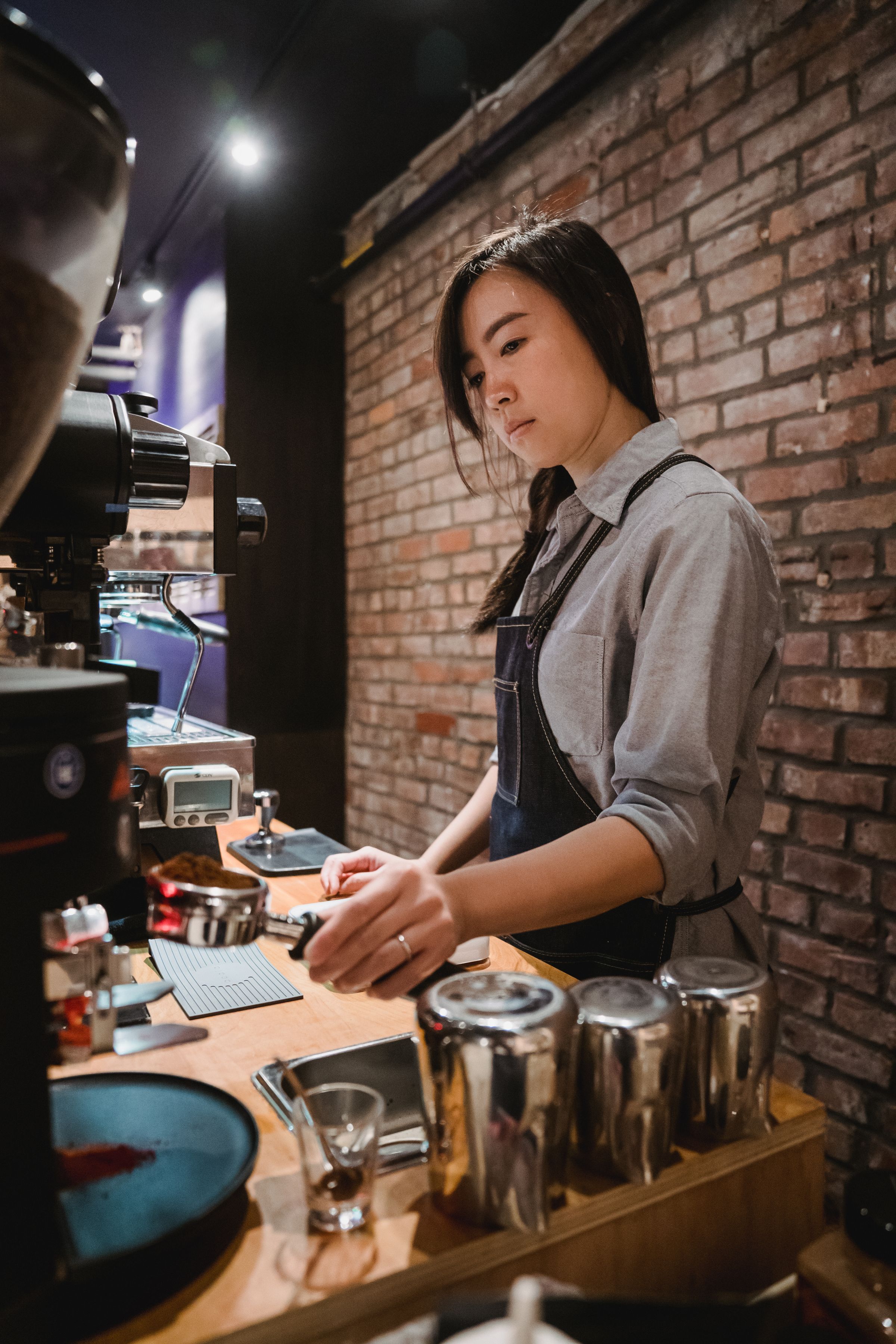 A young worker preparing coffee at a professional espresso machine