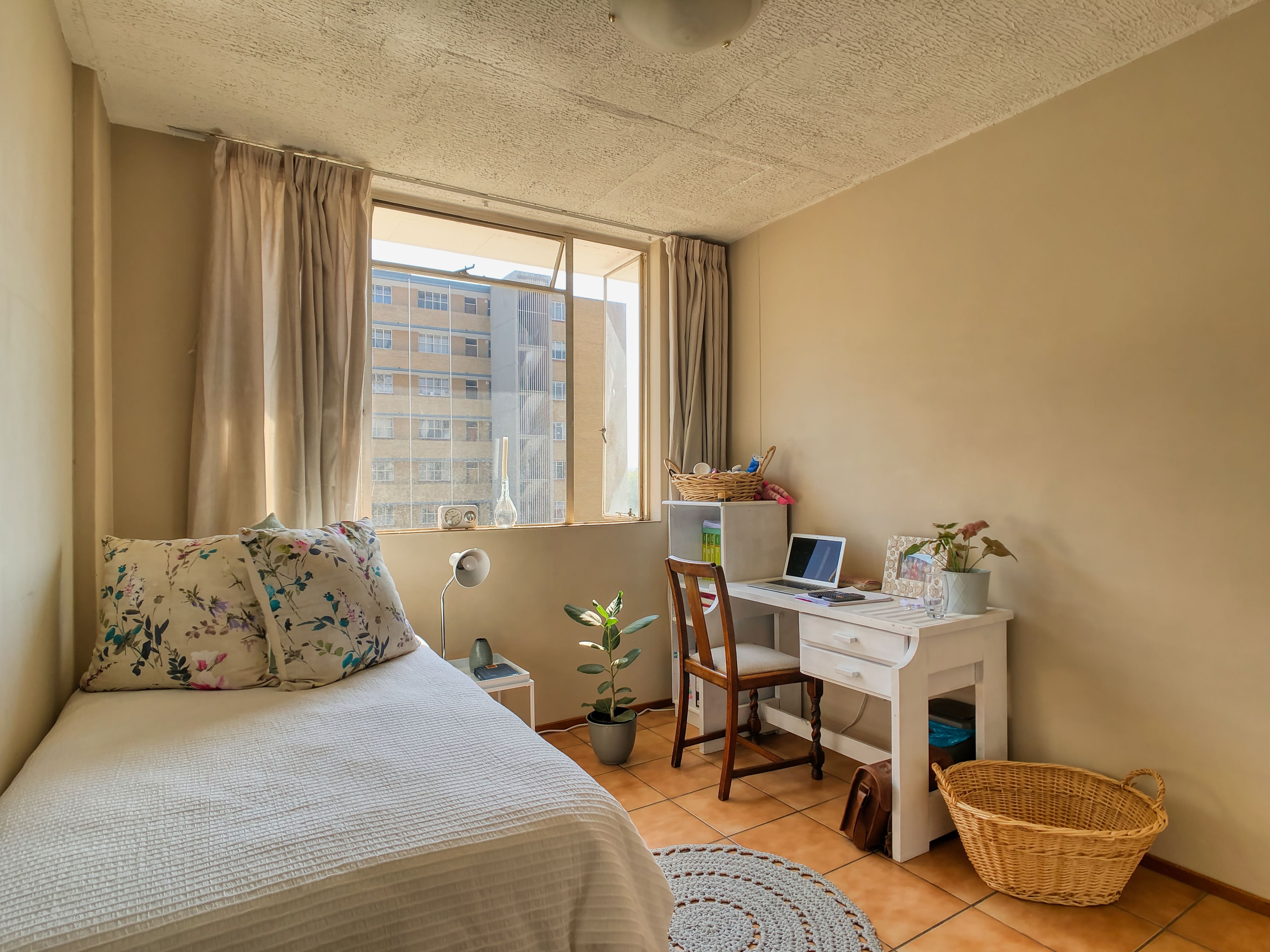 A bright student room with a bed and desk